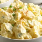 Creamy potato salad served in a bowl with herbs and vegetables